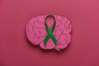 Pembe arka planda kağıt beyinli yeşil farkındalık kurdelesi. Dünya Ruh Sağlığı Günü konsepti