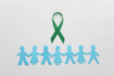 Kağıt ile yeşil farkındalık kurdelesi beyaz arka planda insanları kesiyor. Dünya Ruh Sağlığı Günü konsepti