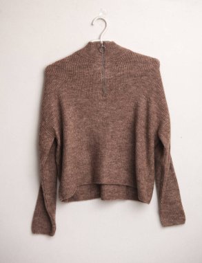 Beyaz arka planda askısı olan kahverengi kadın yün süveteri.