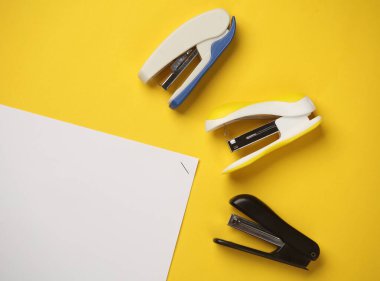 Sarı arka planda kağıt parçaları olan zımbalar. İş konsepti