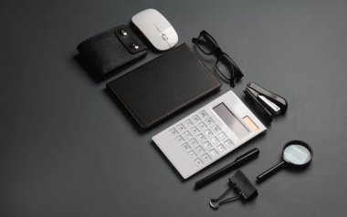 Koyu gri arka planda defter ve kırtasiye malzemeleri. İş konsepti. Yaratıcı yerleşim.