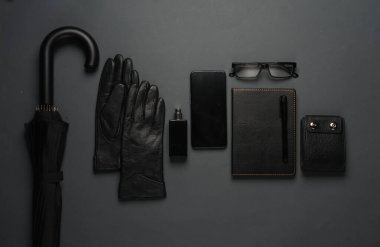 Deri defter, şemsiye, akıllı telefon, parfüm şişesi, eldivenler ve cüzdan. Siyah nesneler. Düz yatıyordu