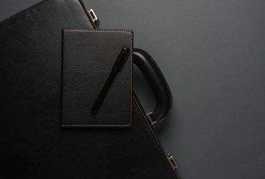 Üzerinde siyah bir defter olan deri bir bavul. İş konsepti. Üst görünüm