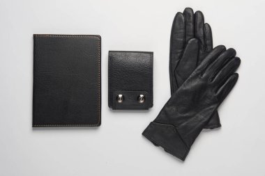 Siyah deri kapaklı ve çantalı defter, gri arka planda eldivenler. İş konsepti. Üst Manzara. Düz yatıyordu
