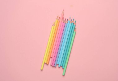 Pembe arka planda renkli kalemler.