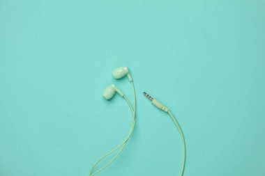 Mavi arka planda kablolu kulaklıklar.