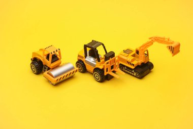 Oyuncak forklift, asfalt kaldıracı ve sarı arkaplanda kazıcı