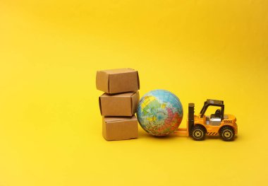 Minyatür oyuncak forklift ve sarı arka planda kutuları olan küre. Lojistik, ulaşım, teslimat