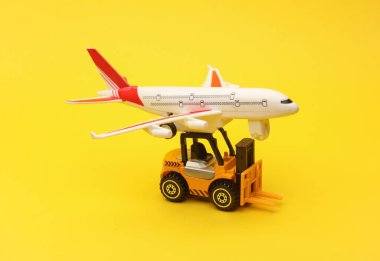 Minyatür oyuncak forklift ve sarı arka planda uçak. Lojistik, ulaşım, teslimat