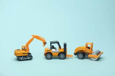 Oyuncak forklift, asfalt kaldıracı ve mavi arkaplanda kazıcı