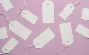 Eflatun arkaplanda ipleri olan boş beyaz etiketler. Tasarım için şablon oluşturun. Satış, alışveriş konsepti