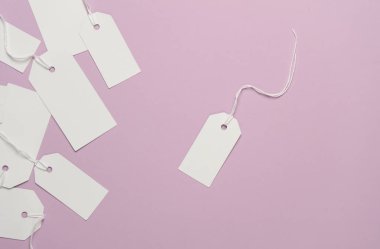 Eflatun arkaplanda ipleri olan boş beyaz etiketler. Tasarım için şablon oluşturun. Satış, alışveriş konsepti