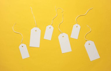 Sarı arka planda ipleri olan boş beyaz etiketler. Tasarım için şablon oluşturun. Uzayı kopyala Satış, alışveriş konsepti