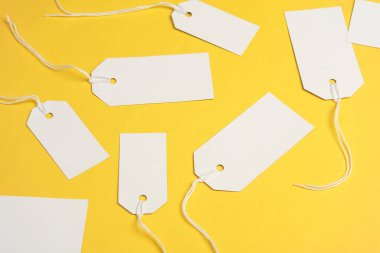 Sarı arka planda ipleri olan boş beyaz etiketler. Tasarım için şablon oluşturun. Uzayı kopyala Satış, alışveriş konsepti