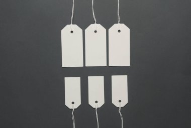 Koyu gri arka planda ipleri olan boş beyaz etiketler. Tasarım için şablon oluşturun. Uzayı kopyala Satış, alışveriş konsepti