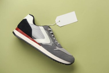 İp üzerinde beyaz boş etiketli gri koşu ayakkabısı, yeşil arka plan. Tasarım, satış ve alışveriş için şablon