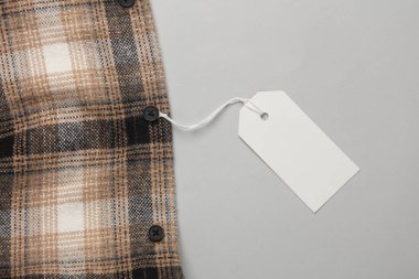 İpin üzerinde beyaz boş etiket olan kareli gömlek. Alışveriş, satış konsepti. Tasarım şablonu