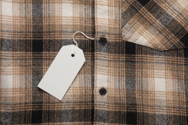 İpin üzerinde beyaz boş etiket olan kareli gömlek. Alışveriş, satış konsepti. Tasarım şablonu