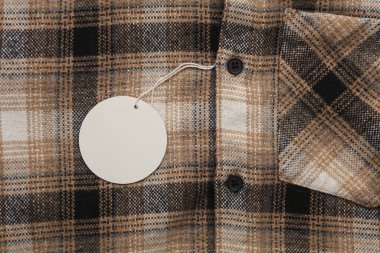 İpin üzerinde beyaz boş etiket olan kareli gömlek. Alışveriş, satış konsepti. Tasarım şablonu