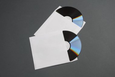 Koyu gri arkaplan üzerine kağıt paketlerdeki CD disklerin maketi
