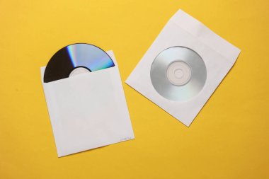 Sarı arkaplandaki kağıt paketlerdeki CD disklerin maketi