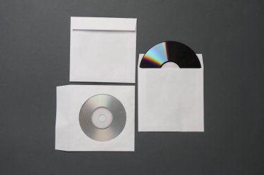Koyu gri arkaplan üzerine kağıt paketlerdeki CD disklerin maketi