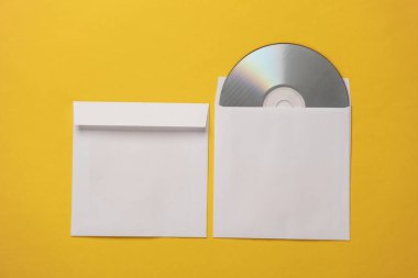 Sarı arkaplandaki kağıt paketlerdeki CD disklerin maketi