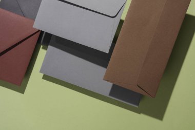 Yeşil arkaplanlı, gölgeli zarflar. Minimalizm, modern iş hayatı