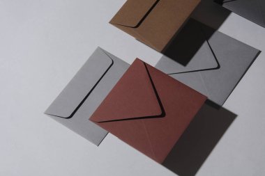 Gri arka planda gölgeli yüzen zarflar. Minimalizm, modern iş natürmort hayat, yaratıcı düzen