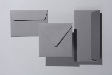Gri arka planda gölgeli yüzen gri zarflar. Minimalizm, modern iş natürmort hayat, yaratıcı düzen