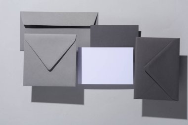 Gölgeli gri arka planda yüzen zarflar ve kartlar. Minimalizm, modern iş natürmort hayat, yaratıcı düzen