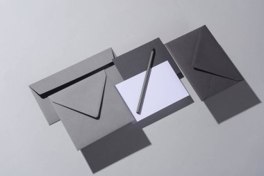 Gölgeli gri arka planda yüzen zarflar ve kartlar. Minimalizm, modern iş natürmort hayat, yaratıcı düzen