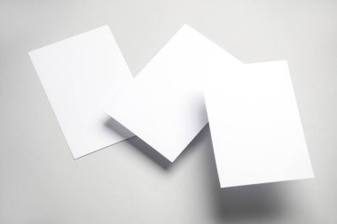 Gri arka planda gölgeli beyaz kartlar yüzdürüyor. Minimalizm, modern iş natürmort hayat, yaratıcı düzen