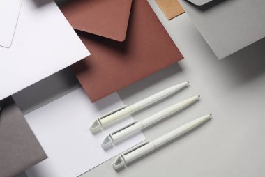 Yüzen zarflar ve kartlar, gri arka planda gölgeli kalemler. Minimalizm, modern iş natürmort hayat, yaratıcı düzen