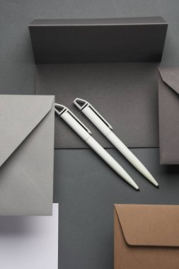 Yüzen zarflar ve kartlar, gölgeli koyu gri arka planda kalemler. Minimalizm, modern iş natürmort hayat, yaratıcı düzen