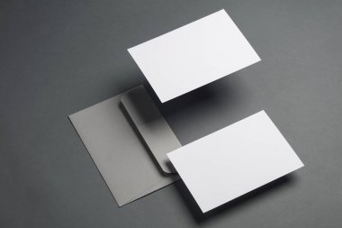 Gölgeli koyu gri arka planda yüzen zarf ve kartlar. Minimalizm, modern iş natürmort hayat, yaratıcı düzen