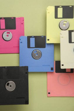 Yüzen renkli 80 'lerin disketleri yeşil arka planda. Kavramsal pop, yaratıcı düzen