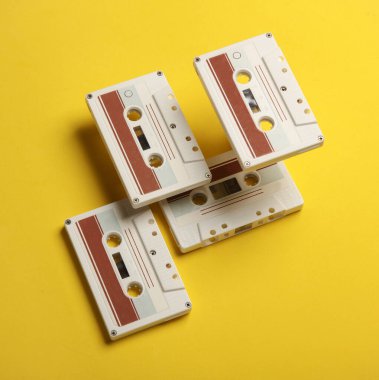 Sarı arka planda 80 'lerin eski ses kasetleri yüzüyor. Kavramsal pop, yaratıcı düzen. Minimalizm