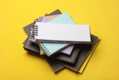 Sarı arkaplana dizilmiş not defterleri