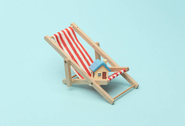 Палубное кресло и миниатюрный домик на синем фоне. Летнее призвание