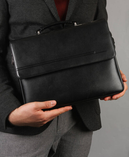 Деловой человек с черным кожаным портфелем на сером фоне