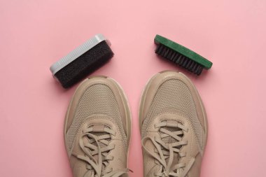 Pembe arka planda süngerli ve fırçalı spor ayakkabılar. Ayakkabı bakımı. Üst Manzara. Düz yatıyordu