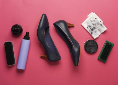 Pembe arka planda ayakkabı bakım ürünleri ve aksesuarları olan yüksek topuklu deri ayakkabılar. Düz yatıyordu