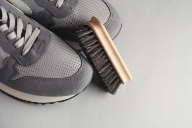 Gri arka planda fırçalı spor ayakkabılar. Ayakkabı bakımı
