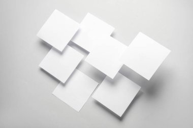 Gri arka planda yüzen beyaz kare not kağıtlarının bileşimi. İş konsepti