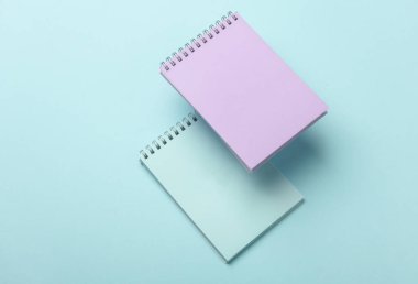 Mavi arkaplandaki yüzen not defterlerinin bileşimi