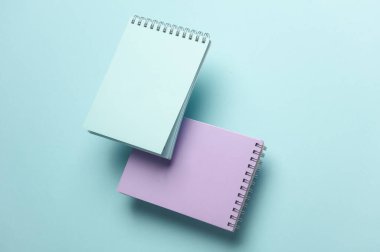 Mavi arkaplandaki yüzen not defterlerinin bileşimi