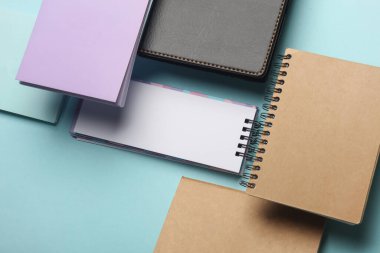 Mavi arkaplandaki yüzen not defterlerinin bileşimi