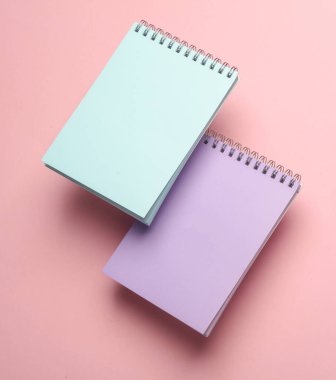 Pembe arka planda yüzen not defterlerinin bileşimi