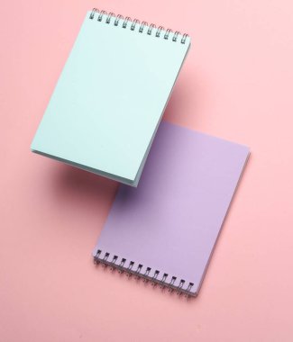 Pembe arka planda yüzen not defterlerinin bileşimi